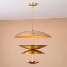 Handcrafted solid brass ceiling light with stacked bowl discs emitting a warm, ambient glow