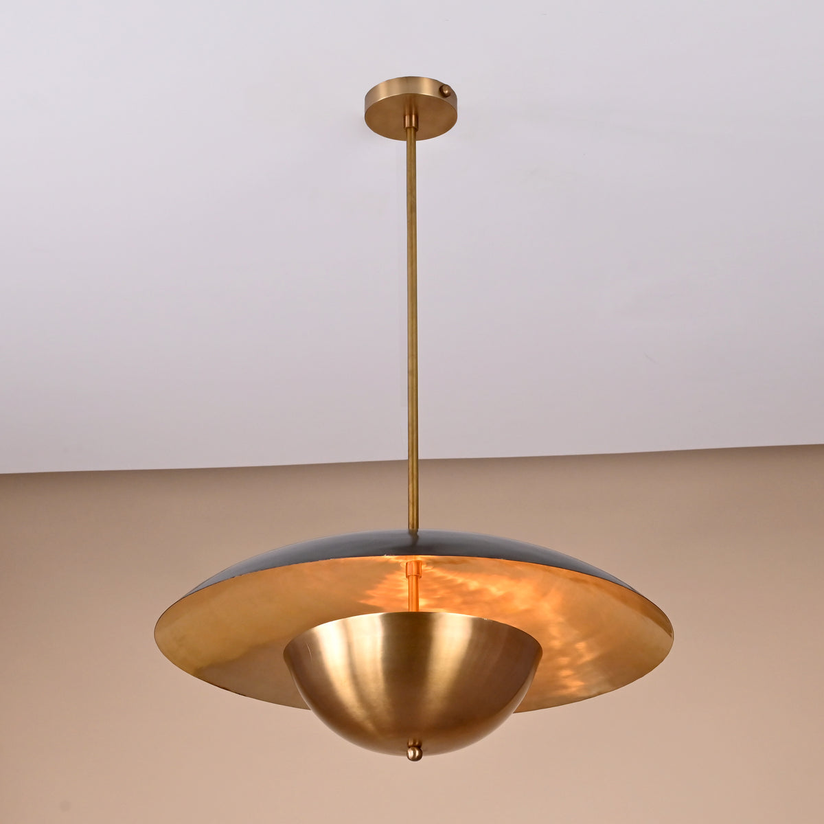 Angled side view of handmade brass ceiling light featuring two contrasting domes and minimalist industrial styling
