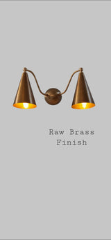 Raw brass dual cone wall sconce with warm interior glow, artisanal handcrafted lighting by Brass Leaf Studio