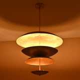 Warm glowing effect of multi-disc brass chandelier highlighting layered sculptural form