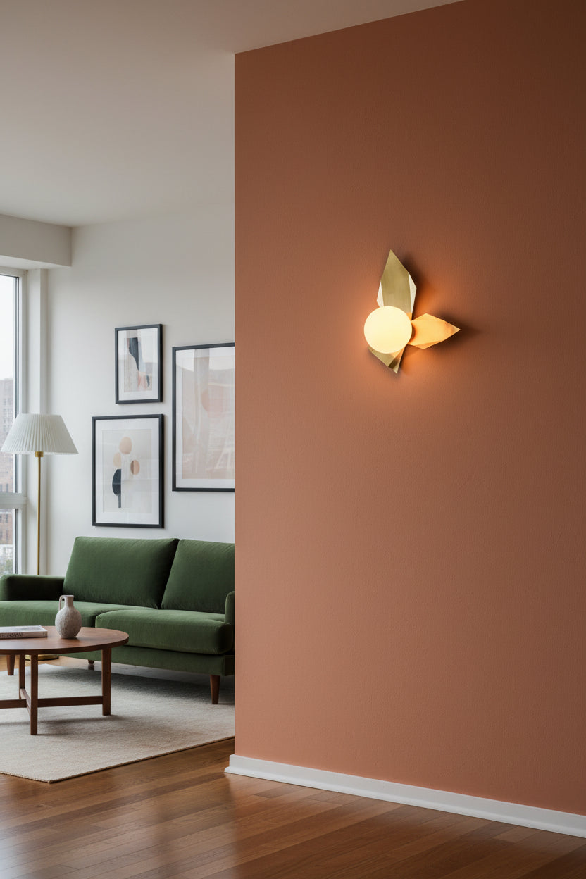Raw brass leaf style wall sconce with glowing round glass globe creating warm decorative wall lighting