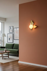 Raw brass leaf style wall sconce with glowing round glass globe creating warm decorative wall lighting