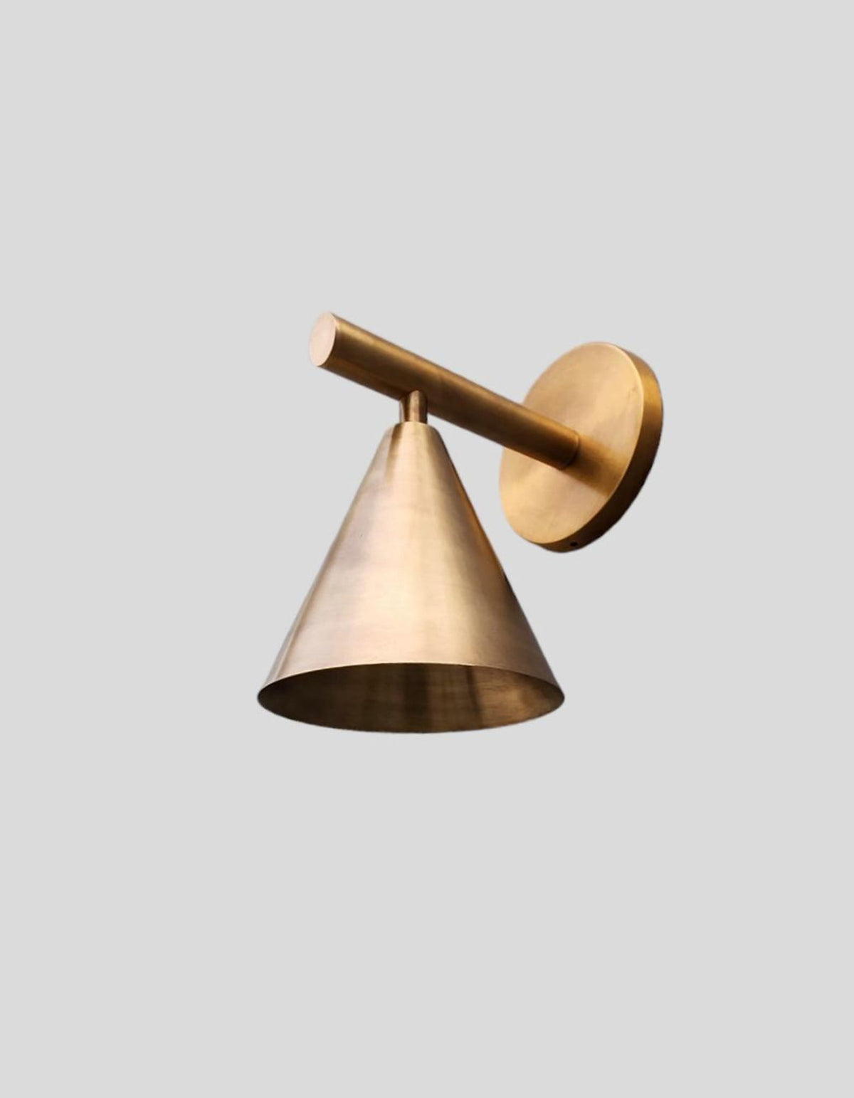 Close-up of raw brass modern cone wall light with precision detailing and soft satin texture, designed by Brass Leaf Studio.