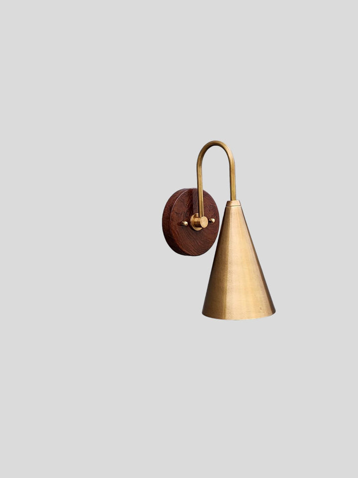 Minimalist brass wall sconce featuring a brushed cone shade and wooden backplate designed for modern interiors by Brass Leaf Studio.