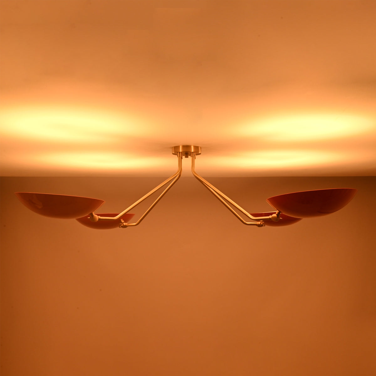 Top view of red disc flush mount ceiling light when lit, showcasing soft uplighting and balanced four light configuration.