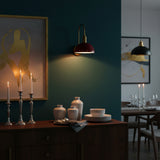 Close-up of red bowl shade brass wall sconce showing smooth glossy finish, round canopy, and warm light output