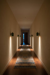 Illuminated Rome brass wall sconce casting warm focused light downward for elegant ambient and accent lighting