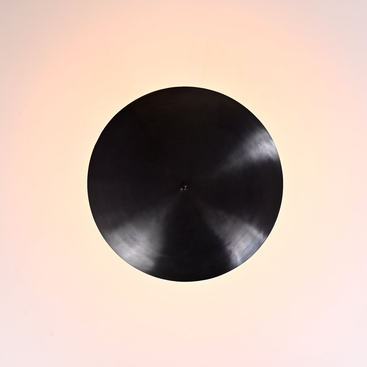 Top view of blackened brass bowl ceiling light showing circular uplight pattern