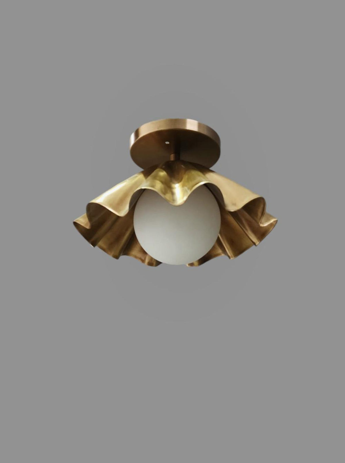 Closeup of handmade ruffled brass flushmount ceiling light, industrial modern design