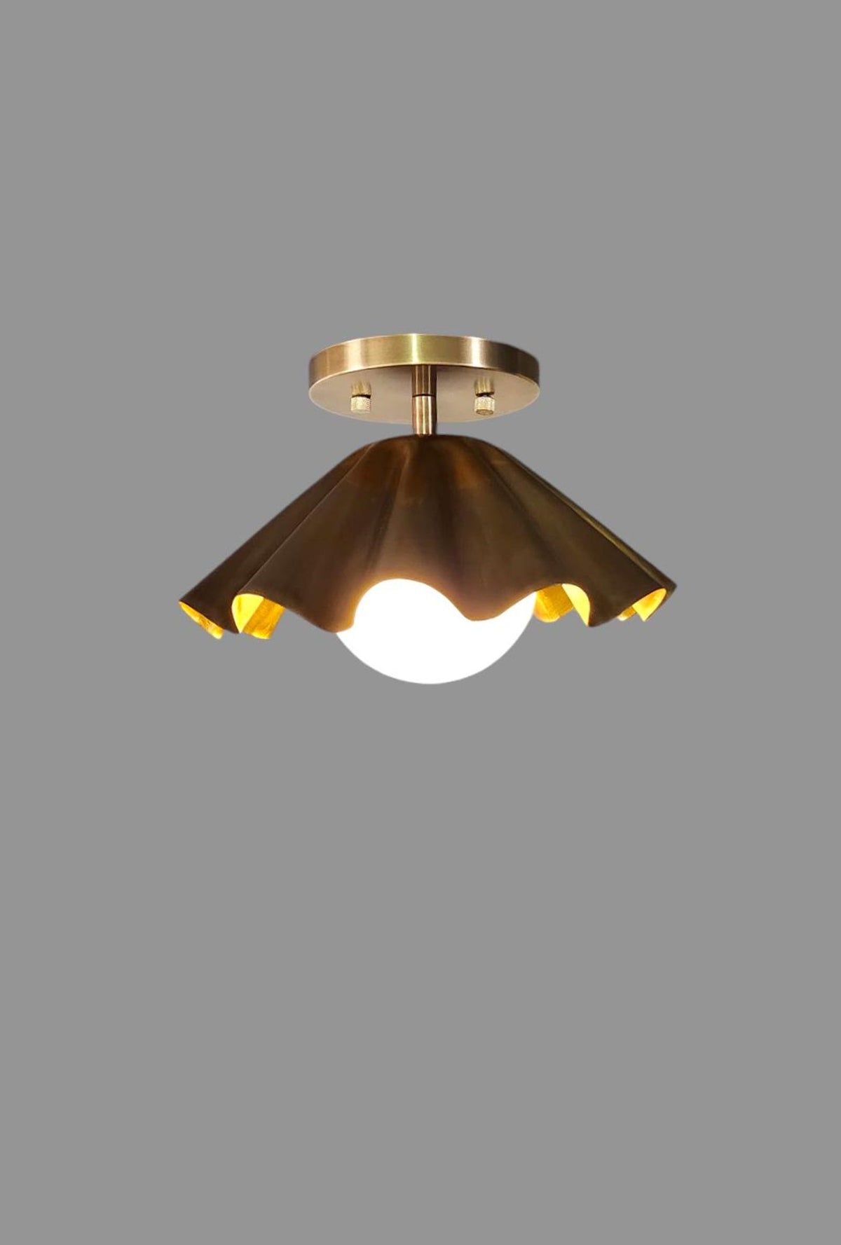 Brass flushmount ceiling light with ruffled shade glowing warmly, modern handmade fixture