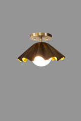 Brass flushmount ceiling light with ruffled shade glowing warmly, modern handmade fixture