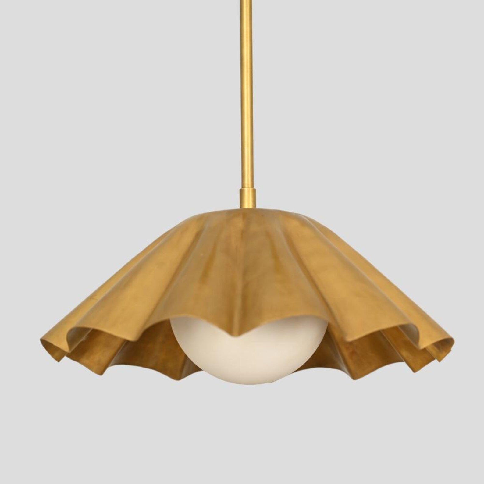 Close-up of ruffled brass pendant chandelier with flowing sculptural shade and globe diffuser, handmade for artistic and modern interior design.