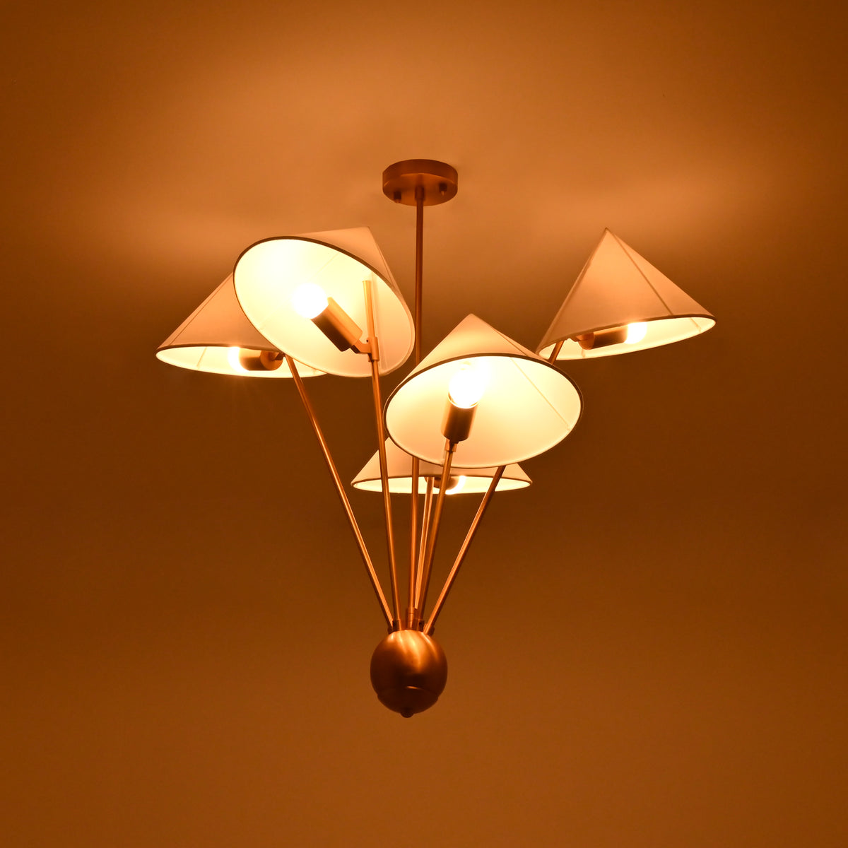 Sculptural five light chandelier with angled white fabric shades and elegant raw brass construction