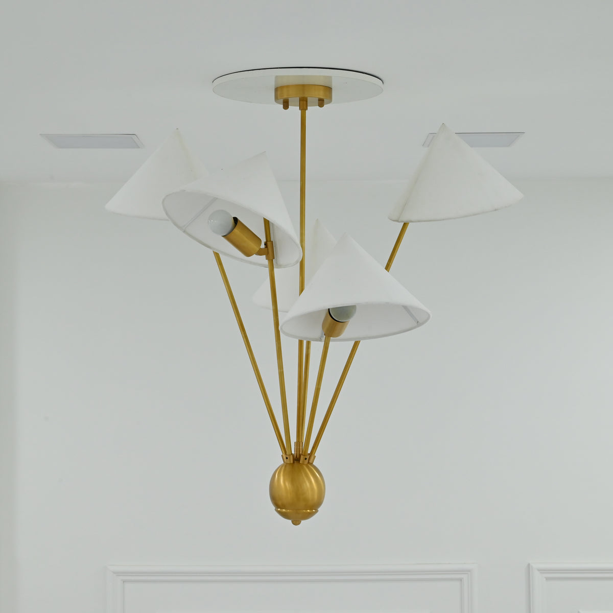Santorini chandelier with five white fabric shades, warm brass framework and softly diffused illumination
