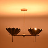 Close view of brass scalloped bowl chandelier casting warm indirect lighting in dark interior