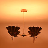 Side view of brass shell shade chandelier illuminated in low light for atmospheric effect