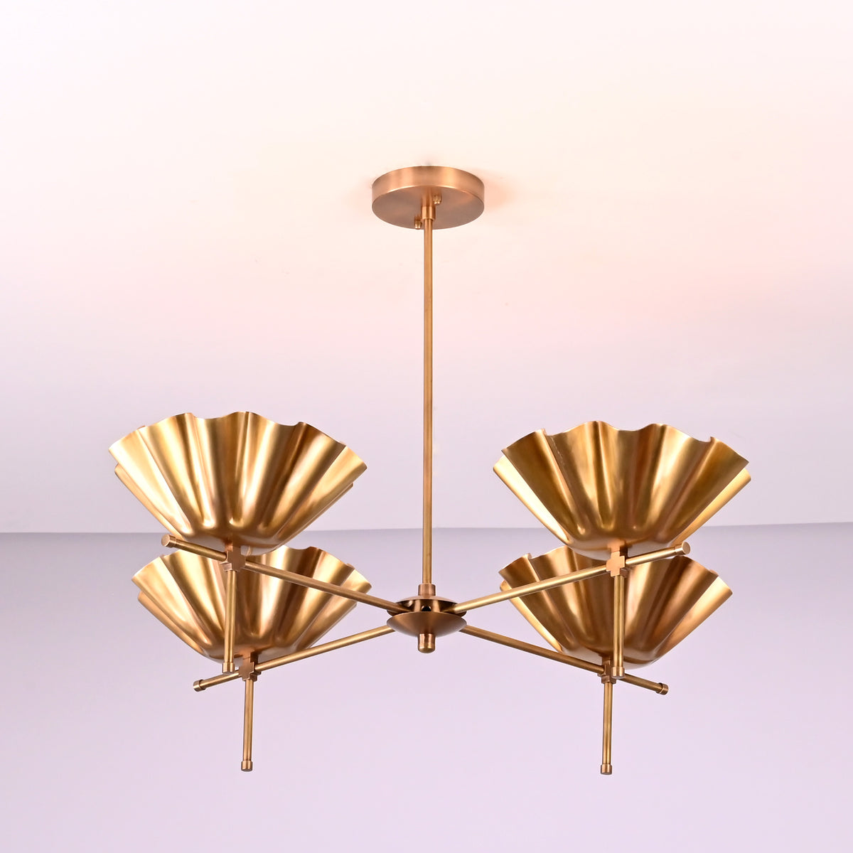 Side angle view of modern brass chandelier with fluted bowl shades and solid brass construction