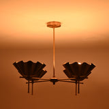 Brass scalloped bowl chandelier glowing warmly in a dark room creating soft ambient light