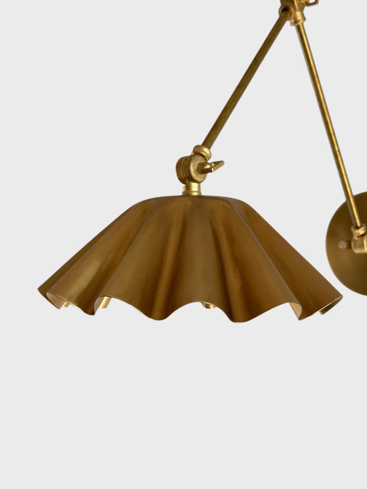 Close-up of scalloped brass shade with fluted folds and warm brushed finish.