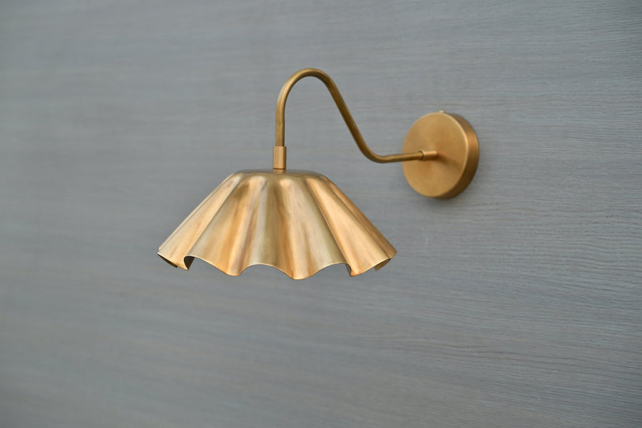 Handmade scalloped brass wall sconce with fluted shade and curved arm – side angle view