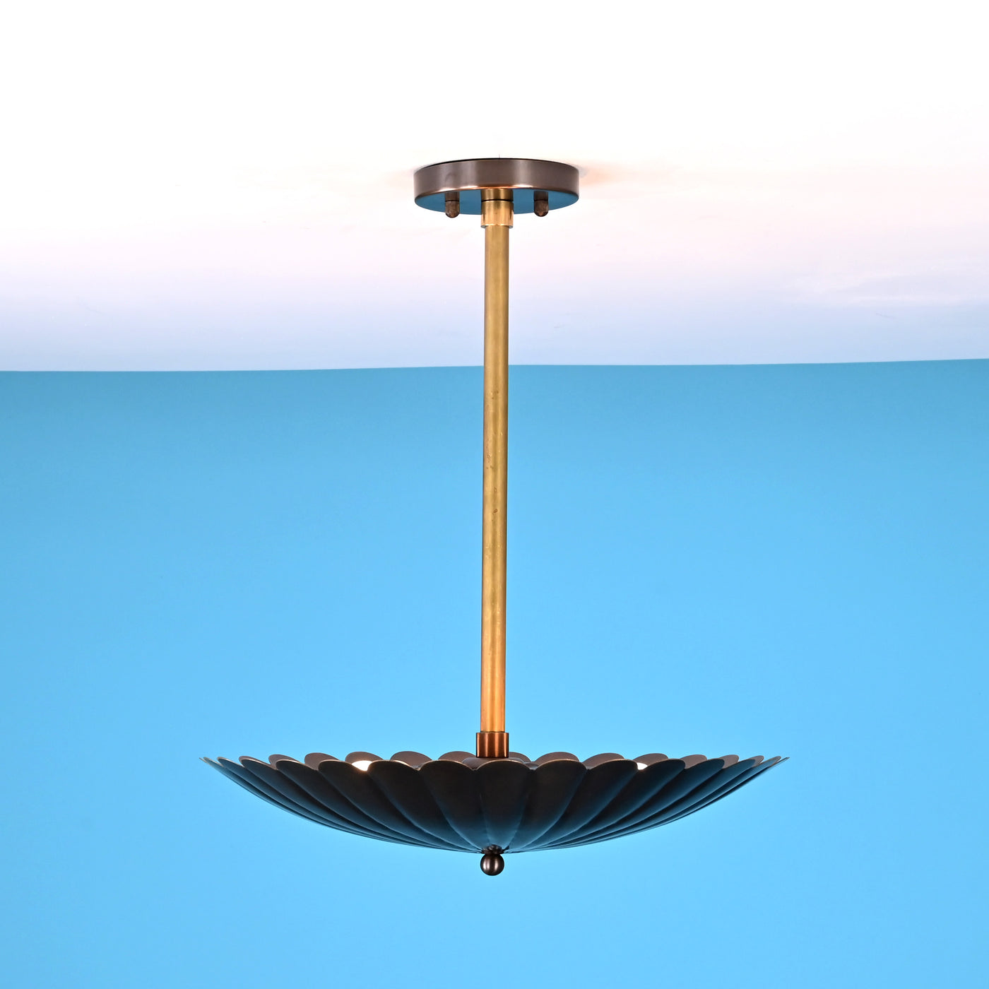 Side angle view of handcrafted scalloped brass pendant light with pleated disc shade