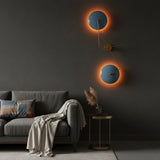 Sculptural blue disc wall sconce shown illuminated with warm halo lighting behind two circular shades