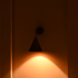 Close view of Seville wall sconce showing lacquer coated brass patina, curved arm and tapered cone shade