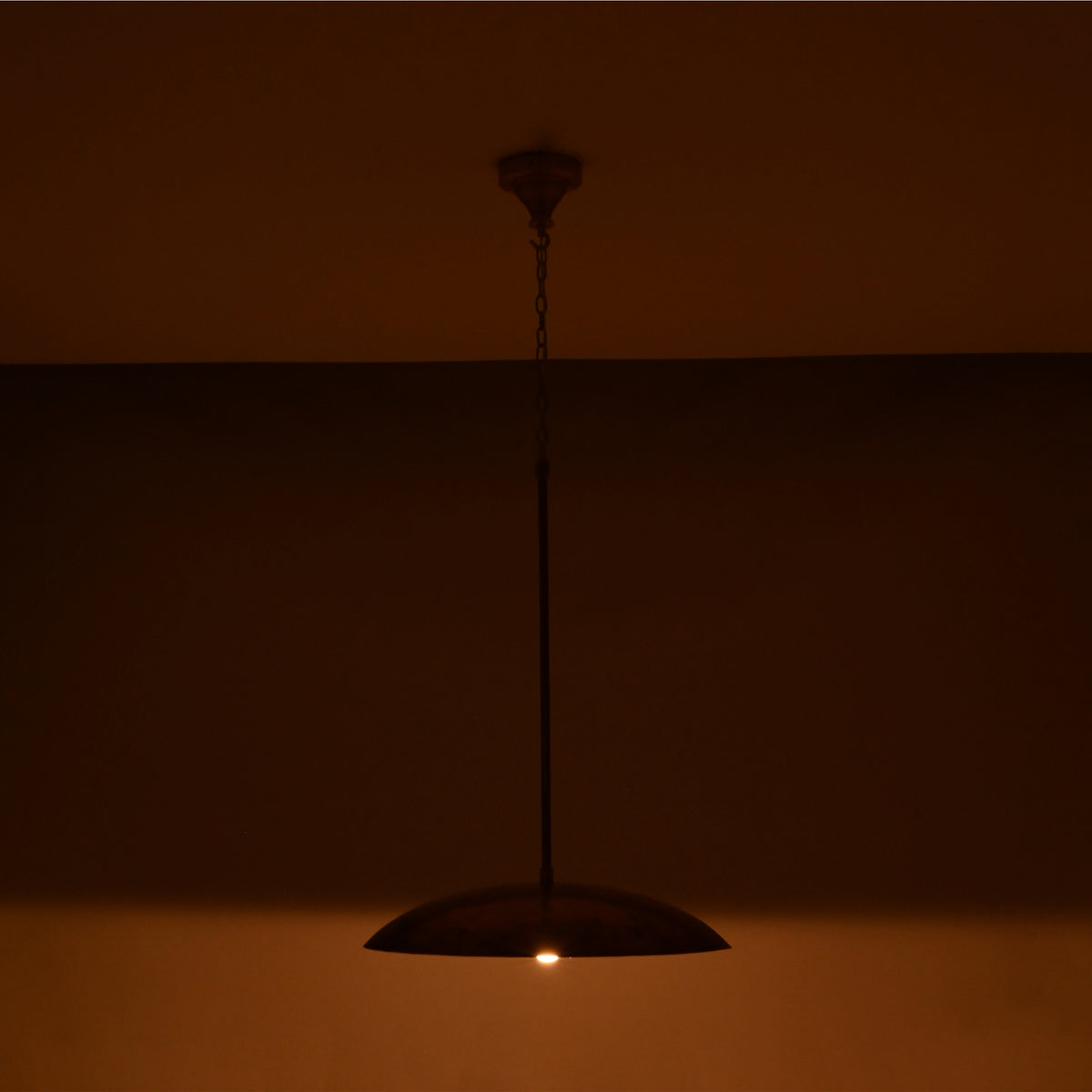 Shallow dome ceiling pendant light with slim suspension rod, chain detail, and warm ambient downward illumination