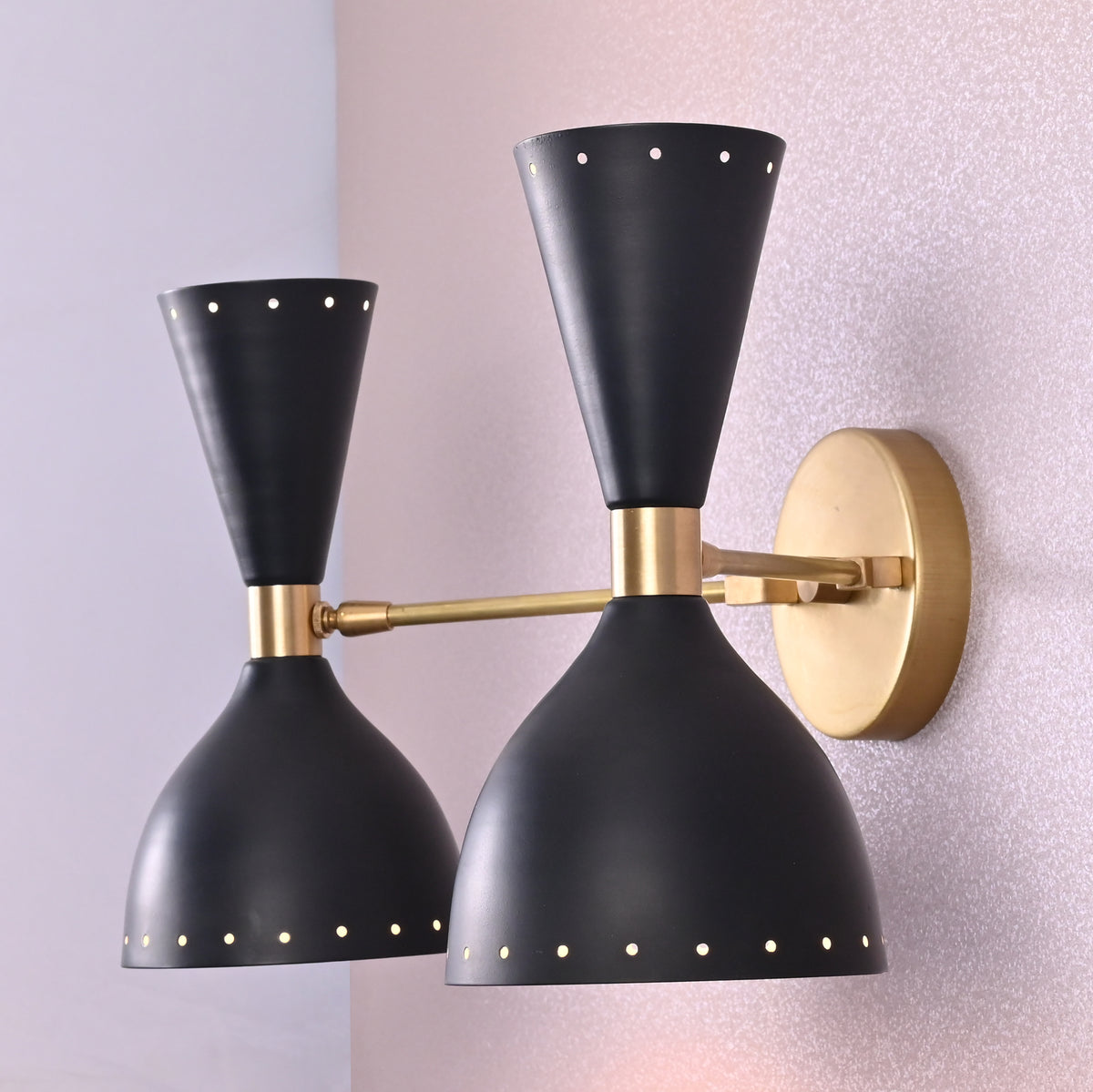 Side angled view of double cone brass black wall sconce with perforated design
