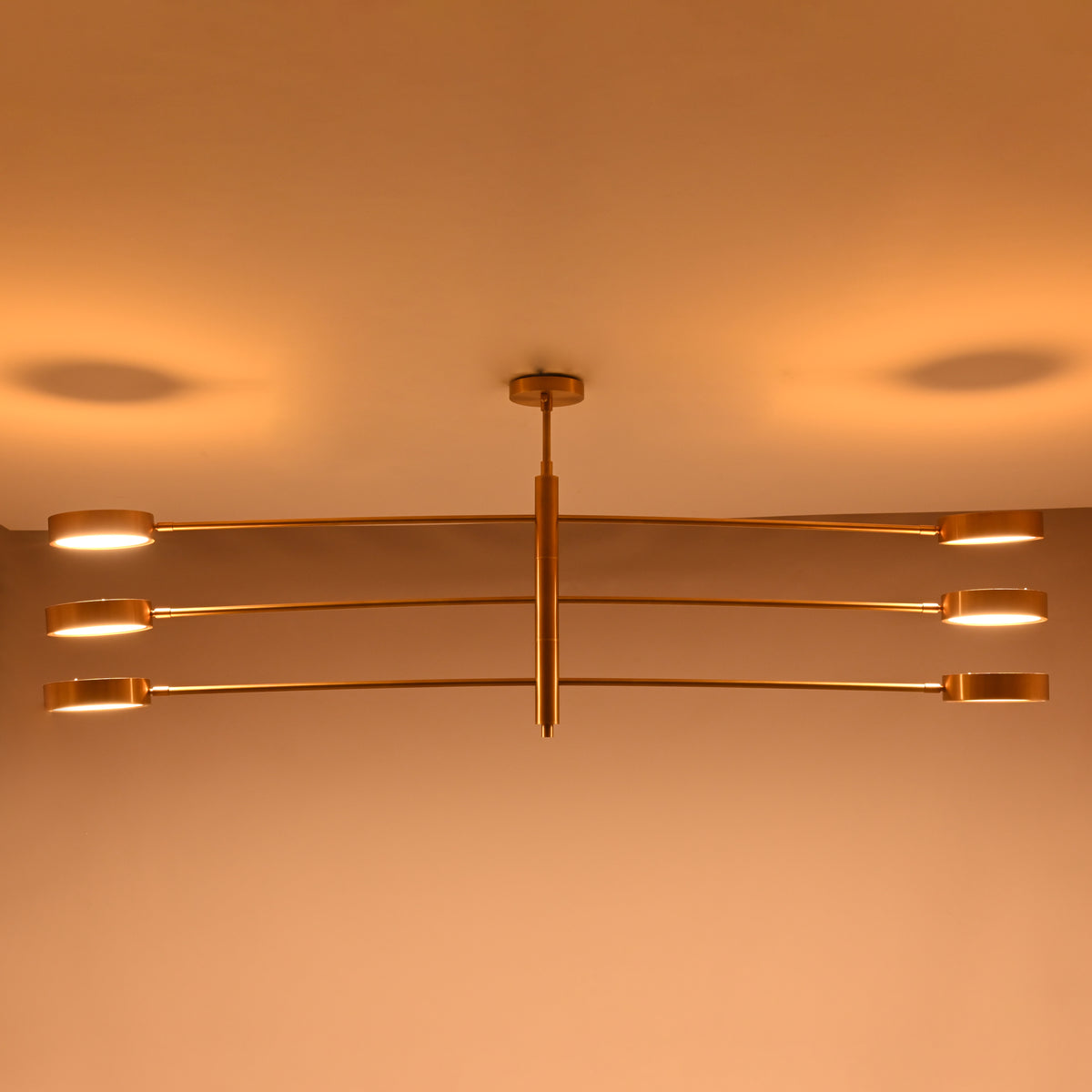 Six-light linear chandelier shown illuminated with broad warm lighting for large rooms and dining tables