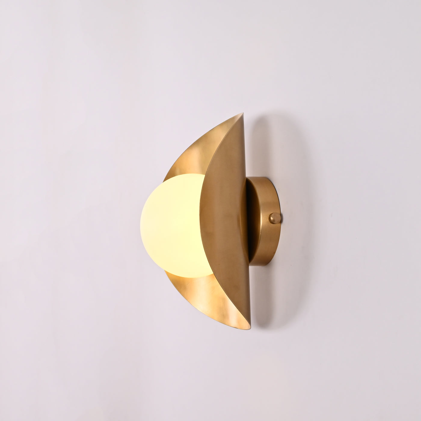 Solara crescent globe wall sconce shown in office interior with warm ambient wall glow
