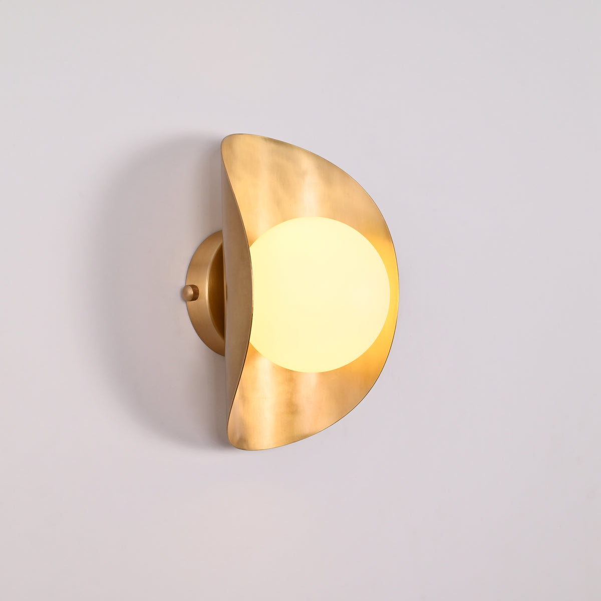 Solara globe wall light closeup showing warm diffused globe and sculptural crescent shield