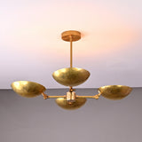 Top angled view of solid brass chandelier with four hammered bowl-shaped shades, highlighting craftsmanship and modern sculptural form.
