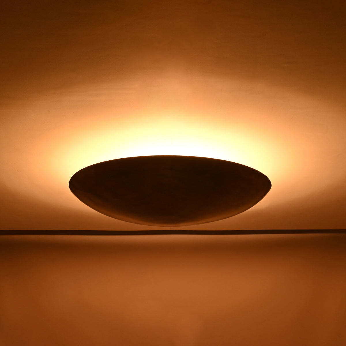 Solid brass bowl flush mount ceiling light shown from front with warm indirect lighting effect
