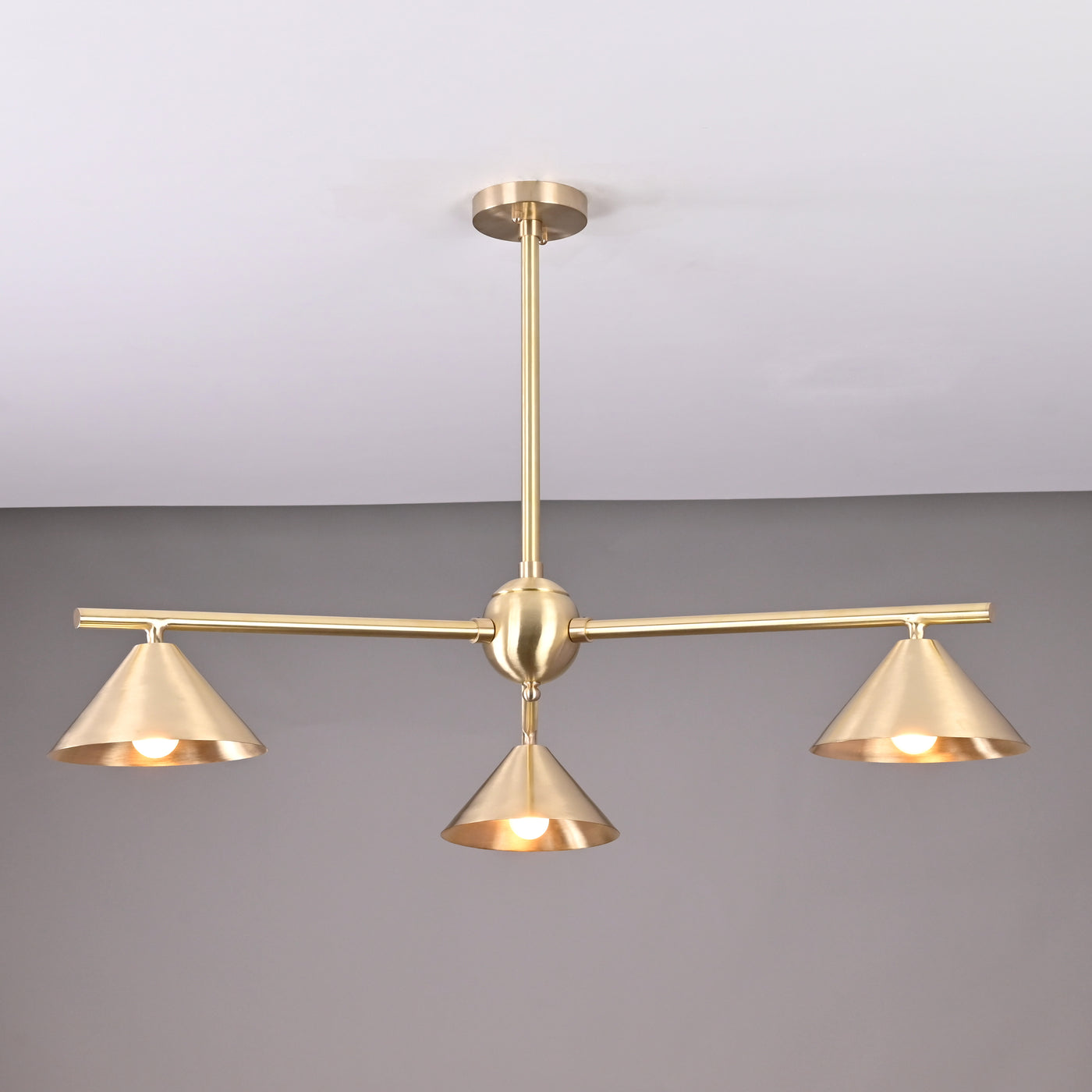 Modern solid brass chandelier with three cone-shaped shades, brushed finish, handcrafted for contemporary interior lighting.