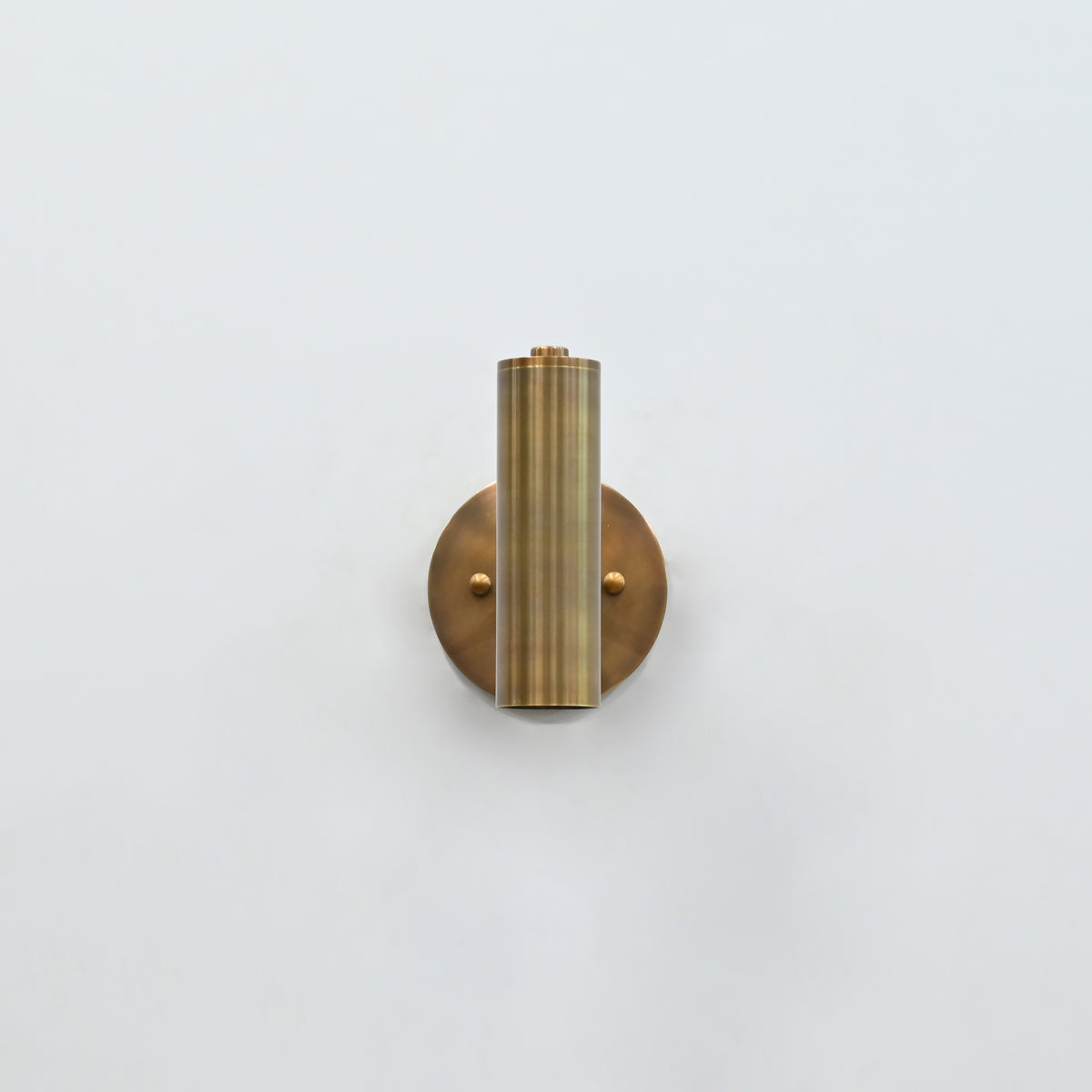 Solid brass cylinder wall light with focused downward glow, ideal for bedside reading and hallway lighting