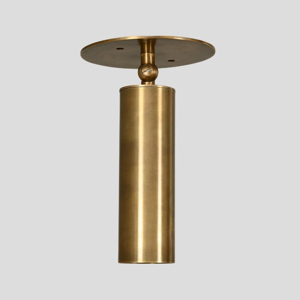Solid brass adjustable cylinder spotlight, front view, handcrafted minimalist industrial ceiling or wall light.