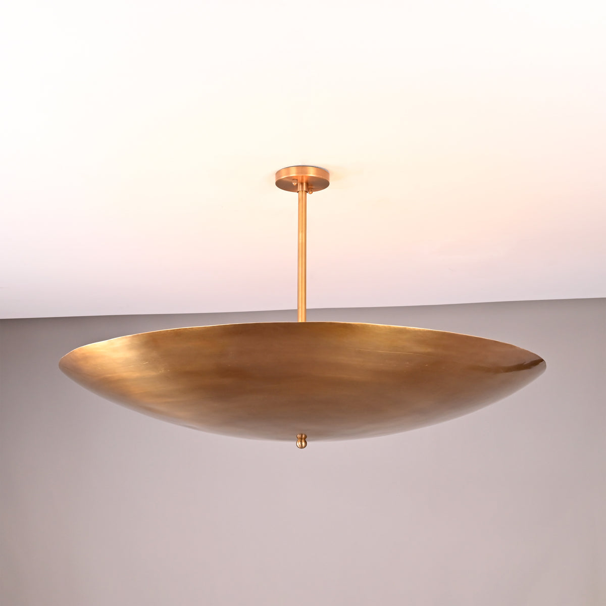 Solid brass disc-style pendant light featuring a wide, shallow bowl design for warm indirect lighting.