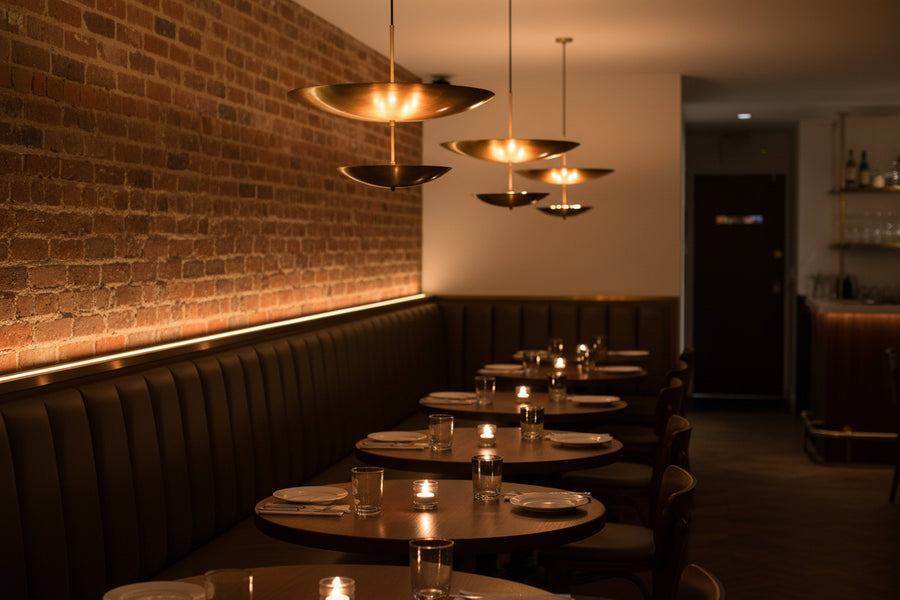 Two-tier brass pendant light with slim downrod, round canopy, and sculptural layered disc profile