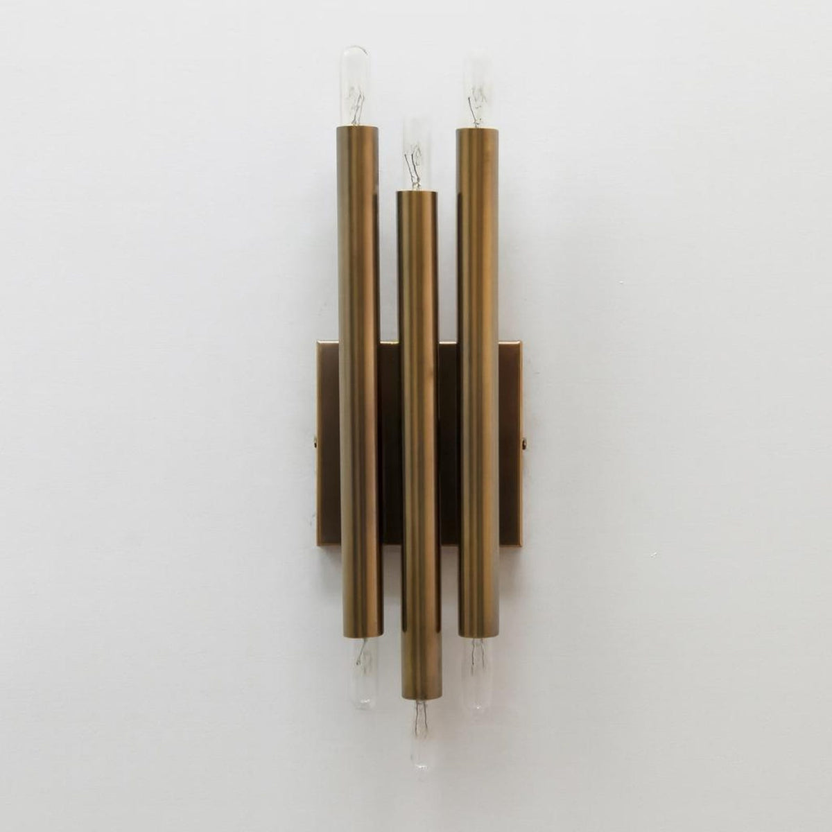 Solid premium brass vertical tube wall sconce close front view highlighting smooth satin finish and exposed filament bulbs