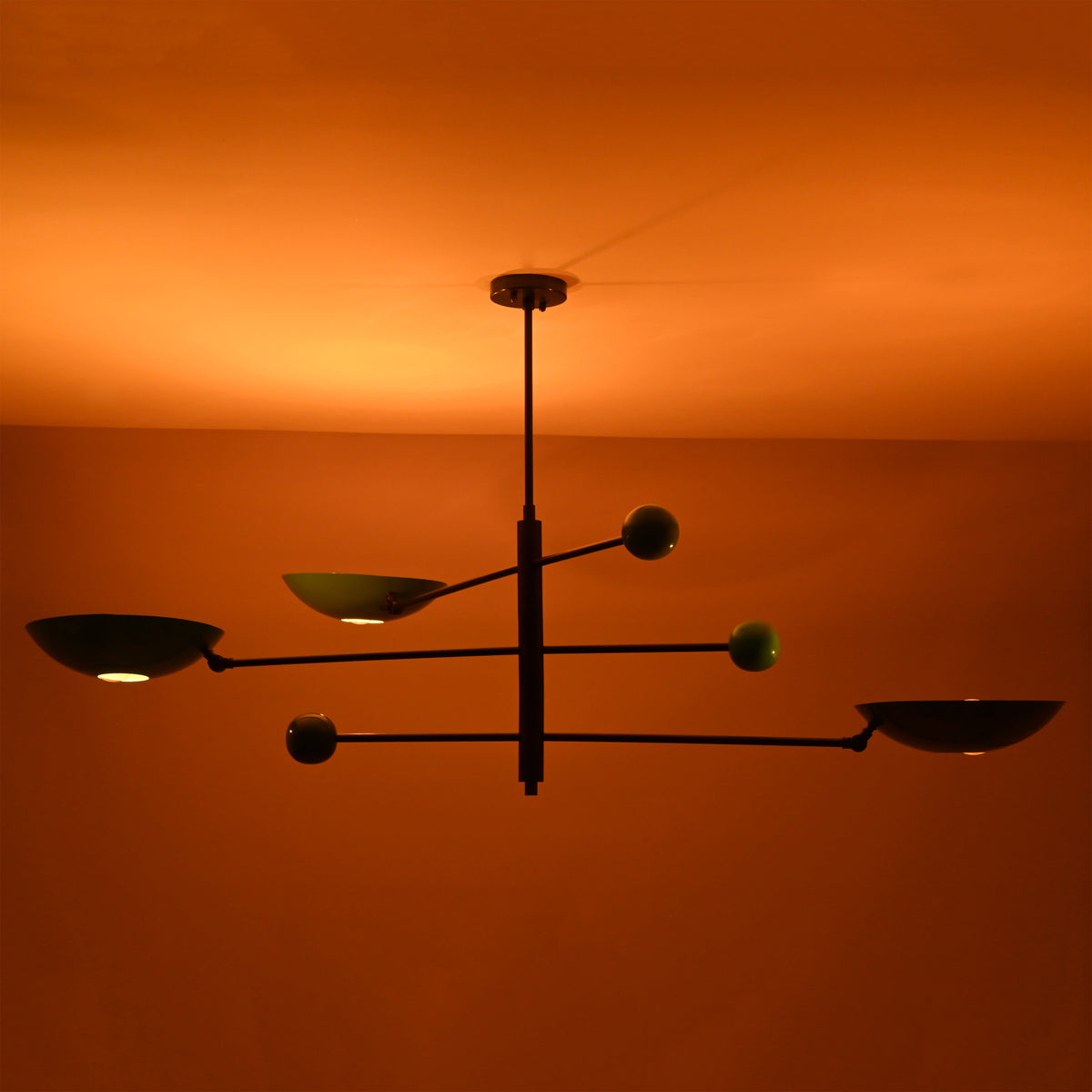 Ambient night view of Sputnik chandelier with colorful disc shades glowing warmly against ceiling