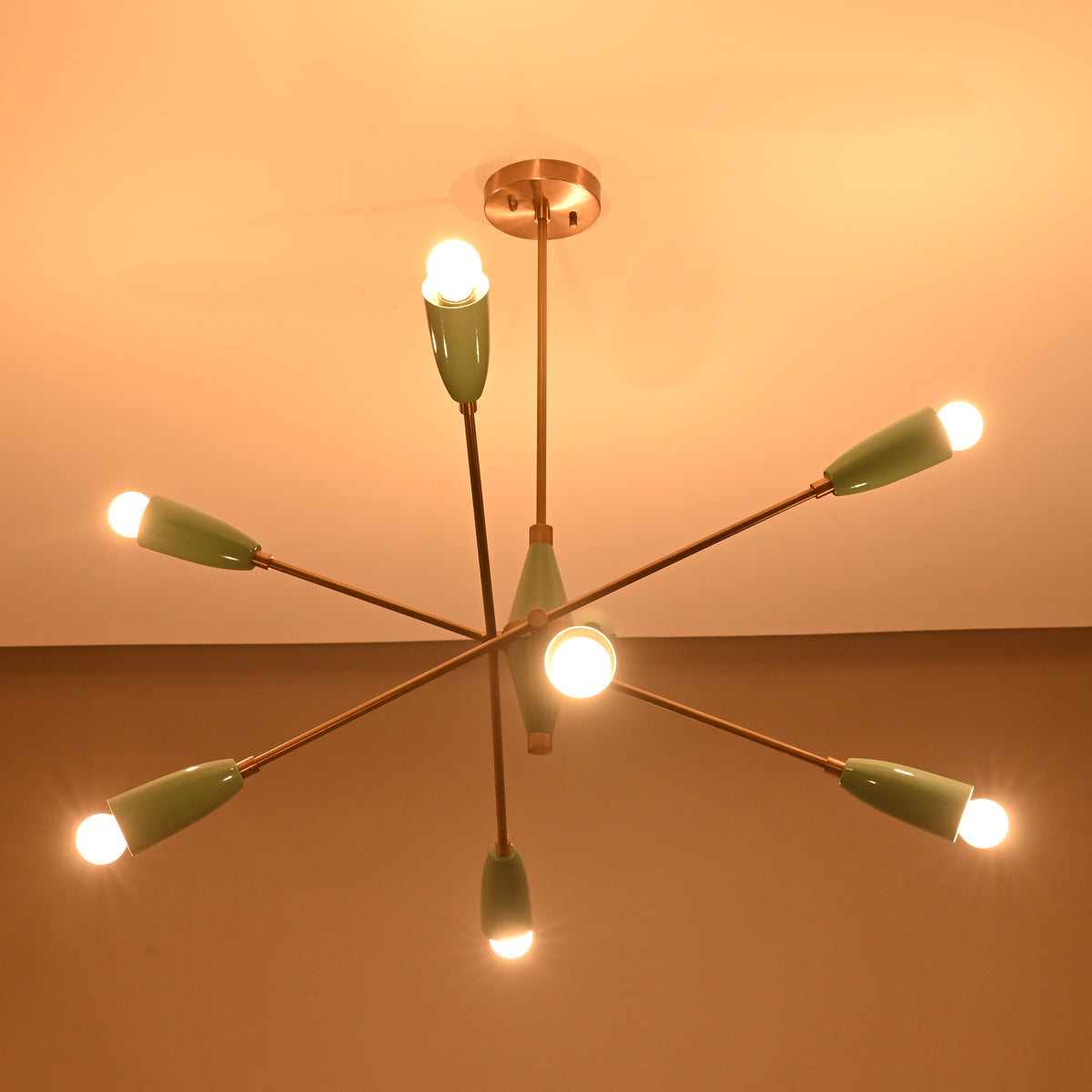 Modern mid-century Sputnik chandelier in teal and brass illuminated warmly, featuring eight angled arms with cone shades.