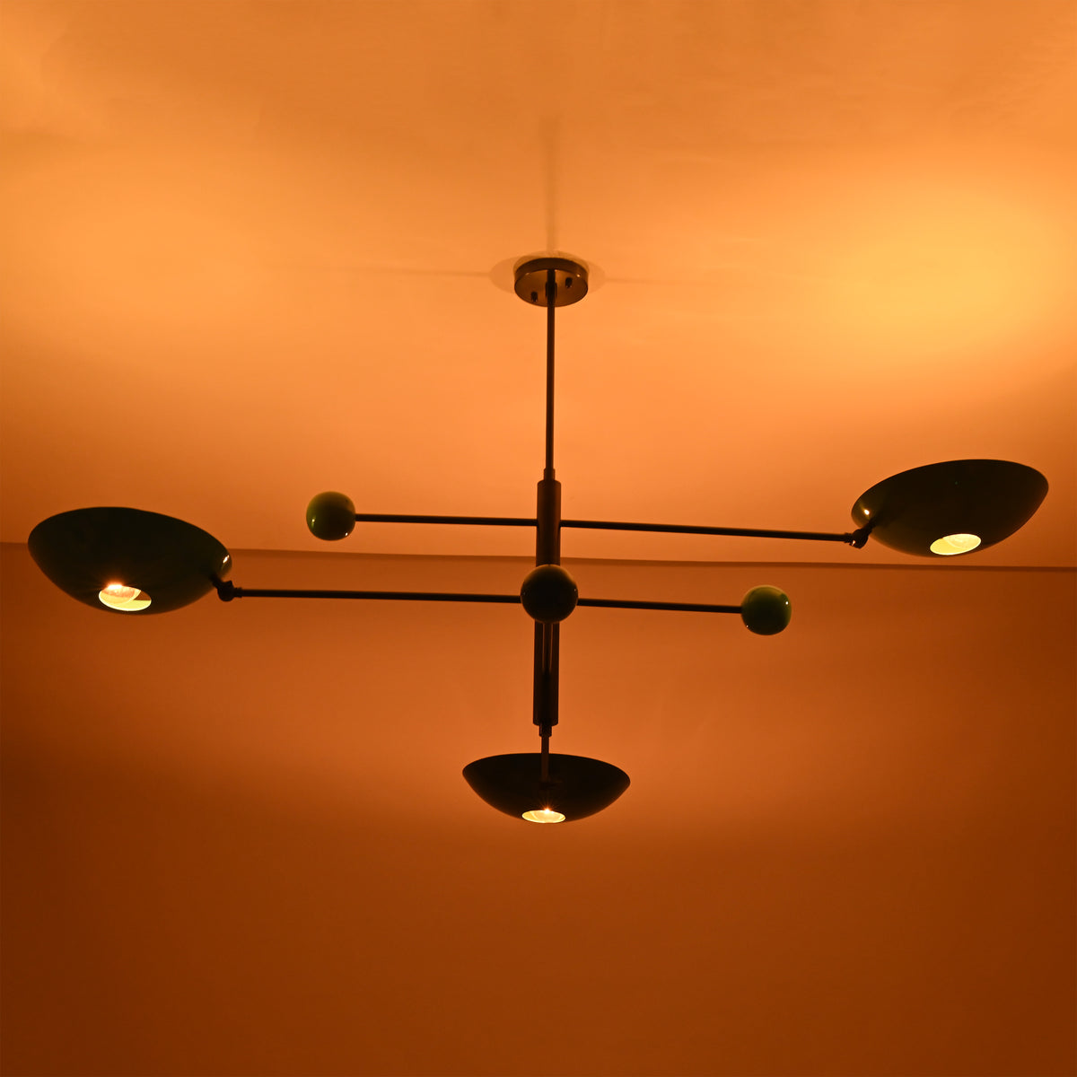 Handmade Sputnik ceiling chandelier with colorful brass disc shades glowing in dark space