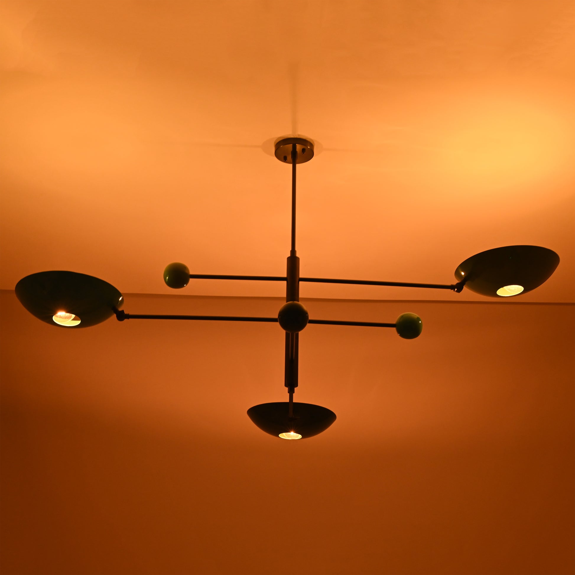 Handmade Sputnik ceiling chandelier with colorful brass disc shades glowing in dark space