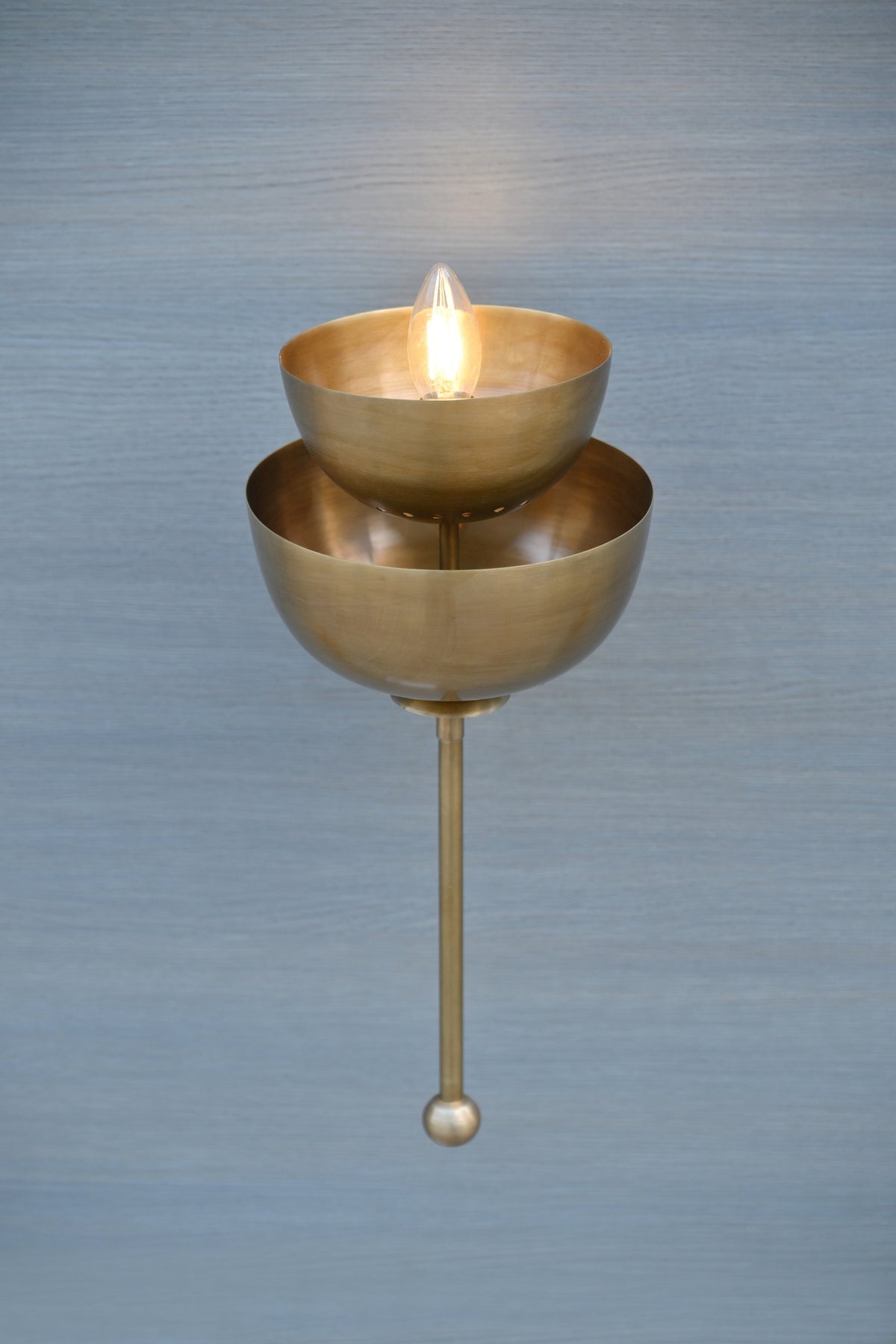 Stacked bowl brass wall sconce illuminated with warm light, handcrafted brass wall decor lighting for interiors