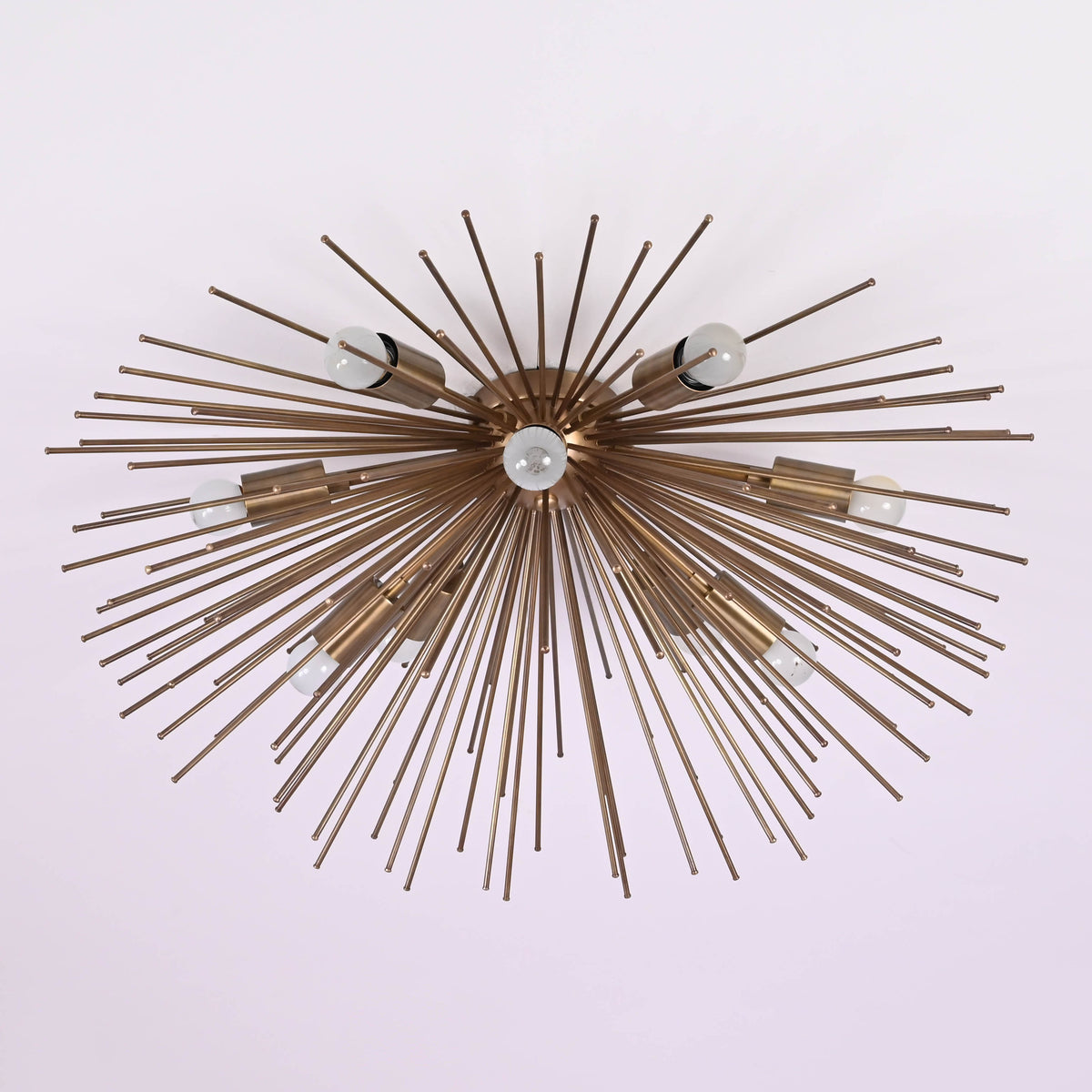 Close-up ceiling perspective of brass sunburst chandelier with exposed bulbs