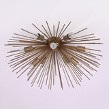 Close-up ceiling perspective of brass sunburst chandelier with exposed bulbs