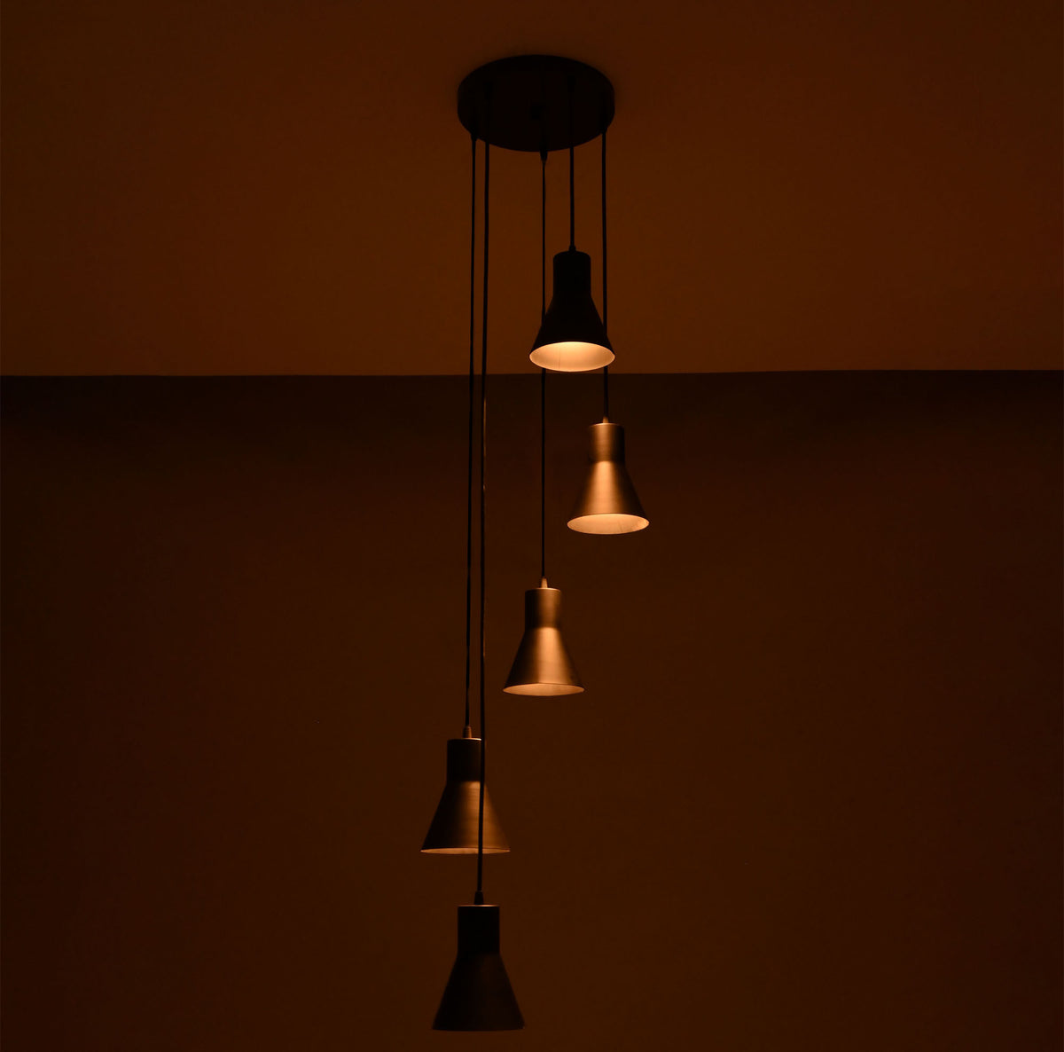 Close perspective of the Sutton Cascade Cone Multi Pendant Chandelier highlighting the warm glow and staggered five-light cascading design.