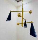 Close-up of handcrafted brass chandelier showing brushed brass finish, cone shade hardware, and premium construction.
