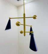 Side view of sculptural three cone chandelier featuring matte black cone shades and handcrafted brass detailing.